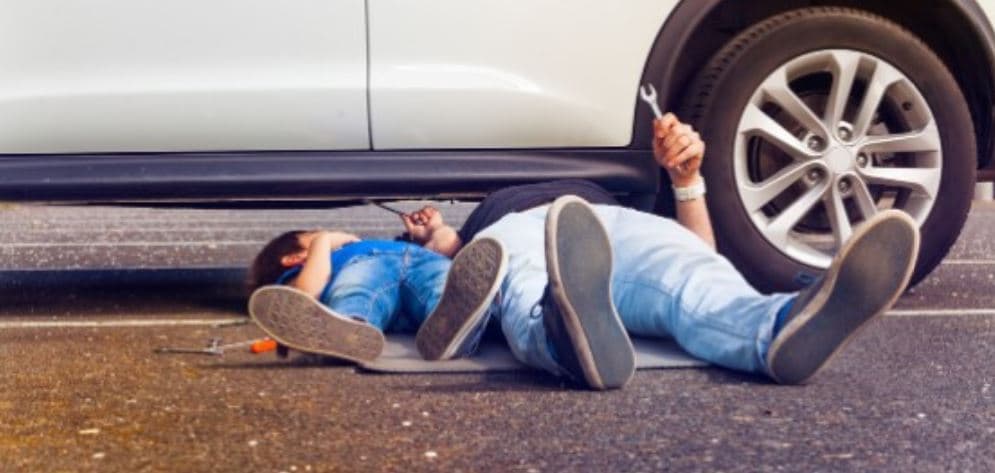 Dad and kid check under the car